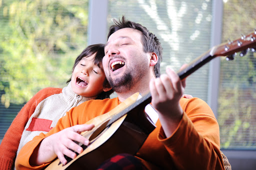 Father and son playing guitar at home &#8211; it