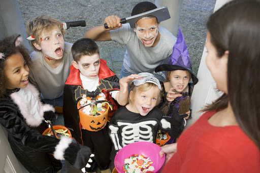 Children in costumes trick or treating at woman&#8217;s house